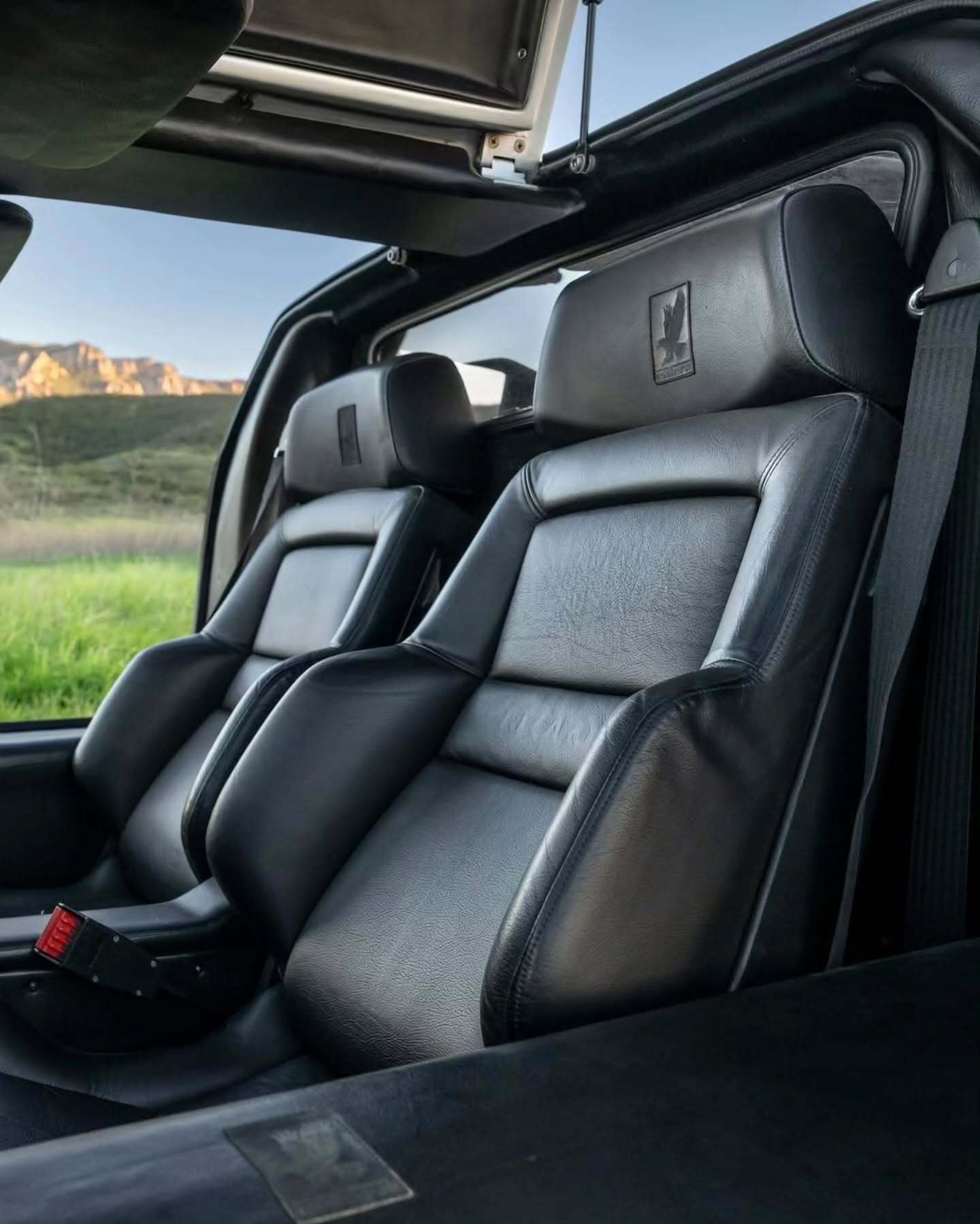 نمای جانبی ابرخودروی کلاسیک ایزدرا امپراتور 108i با رنگ نقره‌ای، آینه پیروسکوپی روی سقف و درهای بال‌کبوتری در یک فضای نمایشگاهی.