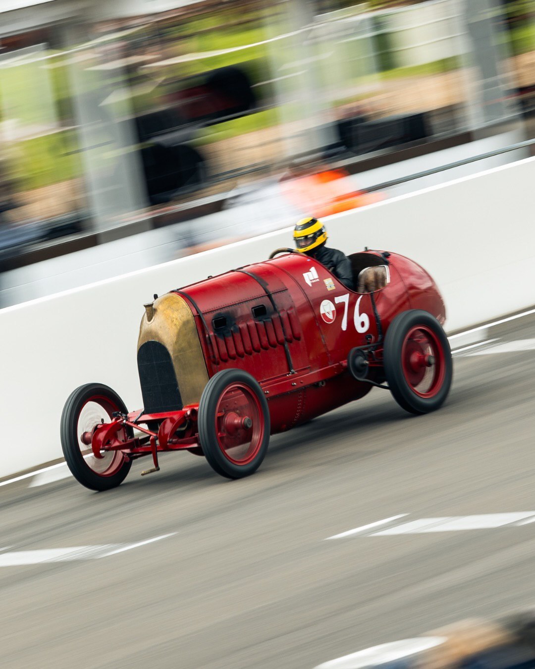 خودروی مسابقه‌ای کلاسیک فیات S76 قرمز رنگ در حال حرکت در پیست و خروج شعله‌های آتش از موتور ۲۸.۴ لیتری.